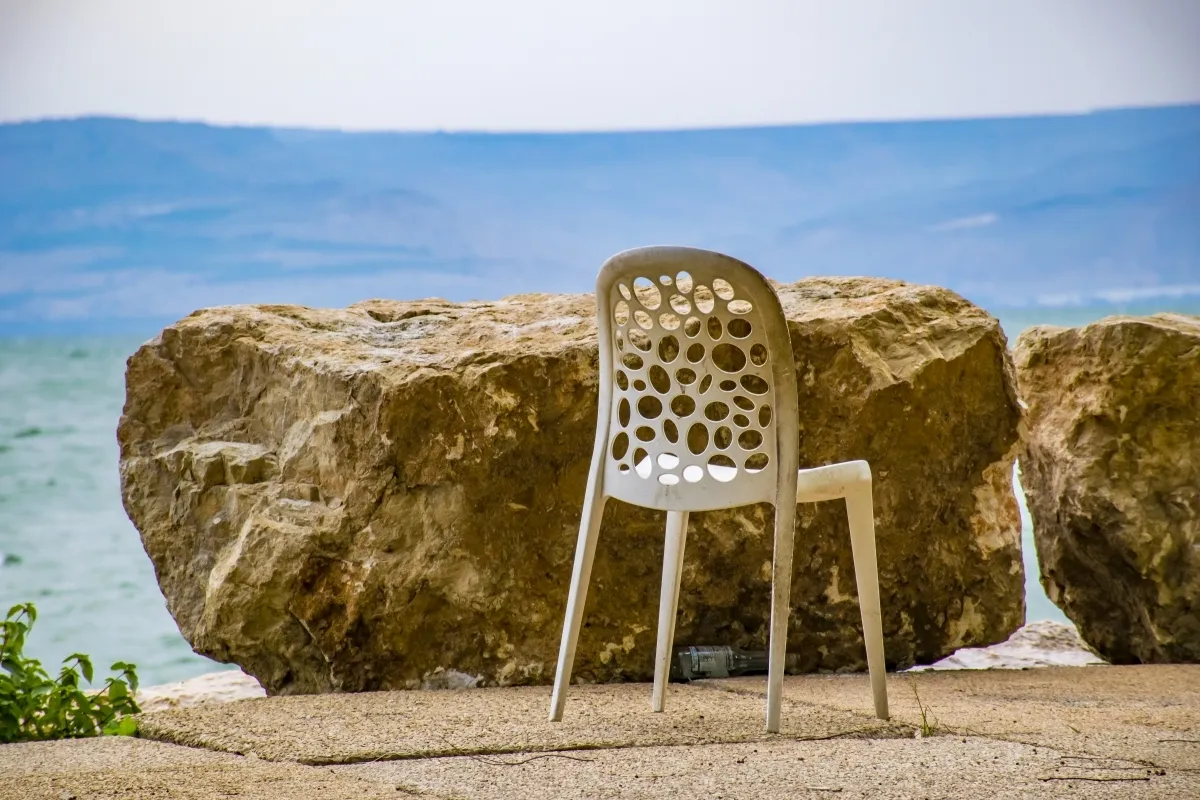 White plastic chair beside large shoreline boulders